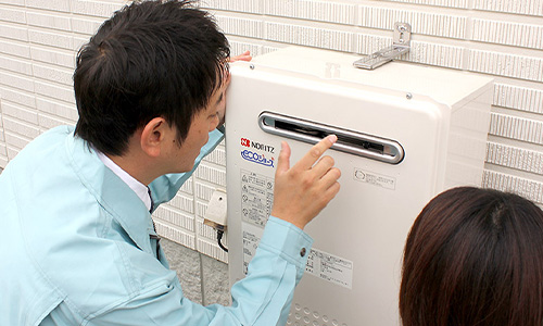 給油機の様子を見る作業員と女性